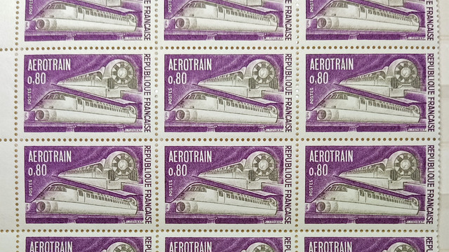 A part-sheet of 12 stamps. Each stamp has a violet background with the subject in grey. The subject is the futuristic design Aerotrain, shown twice, Front and side with ducts on the front, and rear and side, with a large fan on the back. The stamp value is 0.80