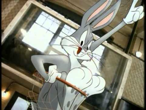 Cartoon rabbit Bugs Bunny with defiant look, feet to chest, crammed into basketball hoop with left arm and index finger raised