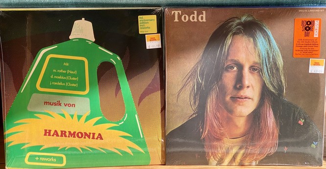 Two vinyl record album covers displayed side by side, one titled "Musik von Harmonia" featuring a green abstract graphic design, and the other titled "Todd" with a close-up photograph of a man with long blonde hair. Both albums have price