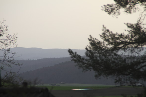 Foto, Blick von der Blockhütte auf den Wahlkreis von F. Merz. In der Ferne drei Hügelketten gestaffelt, jede Kette in einem anderen Graugrünton.