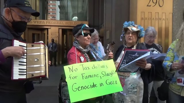 Protest with singing grannies in front of Federal Building. One has a sign, "No tax dollars for famine, slaughter, genocide in Gaza." Accordion Player grandpa plays along.