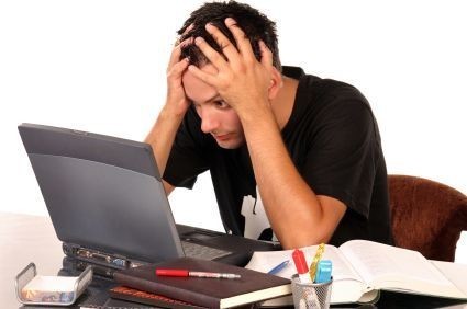 The Rule of Three: a photograph of a man with his head in his hands staring at a computer on a desk