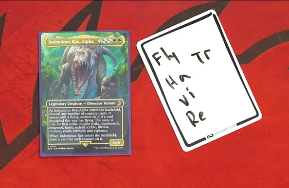 A playmat with Indominus Rex, Alpha on it. Sitting next to it is an InfiniToken Dry Erase Token that says "Fly, Ha, Vi, Re, Tr"