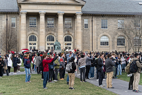 A few hundred people in front of a two-story stone building with four greek columns.