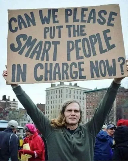 Man holding a cardboard sign over his head reading:

"Can we please put the smart people in charge now?"