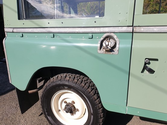 Rear half view of a 1961 Series IIA Land Rover. None of the panels are the same shade of green.