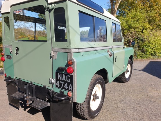 Rear three quarters view of a 1961 Series IIA Land Rover. None of the panels are the same shade of green.