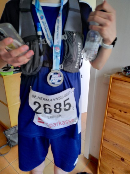 Der Rumpf eines jungen Mannes. Laufkleidung in Blau, Medaille, Startnummer.