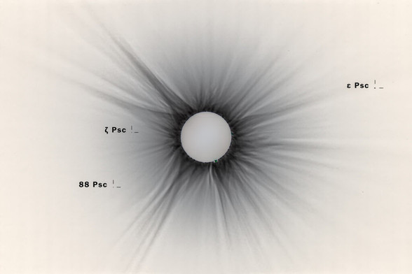 Inverted corona composite image of the total solar eclipse 2024, showing dark streamer and annotated stars in Pisces.