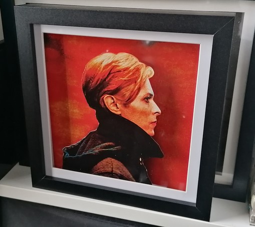 David Bowie's album cover for Low rendered in a shadow box with Bowie's iconic profile separated and in the foreground with the orange background furthest back. His profile casts a shadow. Black framed square box frame.