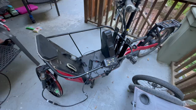 A front wheel spins on a red cargo ebike