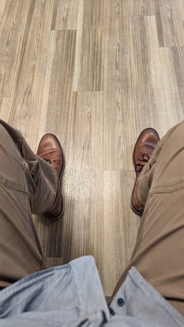 das Bild zeigt den Wartezimmerfussboden mit meinen Beinen und Schuhen