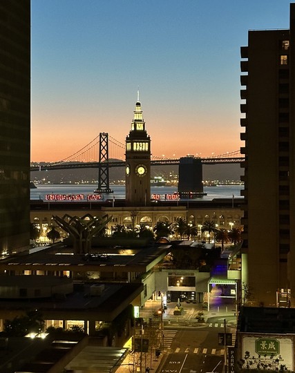 sunrise behind the San Francisco Bay Bridge and Ferry Building Clock Tower.