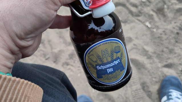 A hand holding a bottle of Schumacher Alt-Bier.