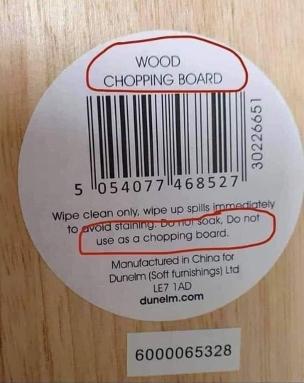 Image of a piece of wood with a sticker on it. The Text on the sticker reads:
"Wood Chopping Board"
followed by a barcode
Then the fine print instructions:
"Wipe clean only, wipe up spills immediately to avoid staining. Do not soak... (and the kicker):
Do not use as a chopping board."
Manufactured in China for Dunelm (Soft furnishings) Ltd.