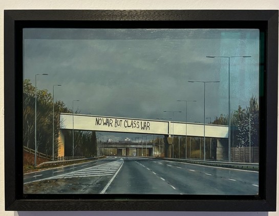 Motorway overpass with graffiti "No war but class war". Grey sky, forest on the verges.