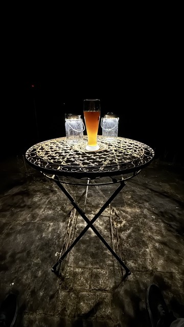 Round garden table with a Hefeweizen at night - framed on the left and right by two solar lanterns.