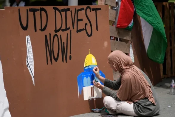A woman paints on a barrier during a protest set up in a plaza at the University of Texas at Dallas on May 1, 2024, in Richardson, Texas [LM Otero/AP Photo]