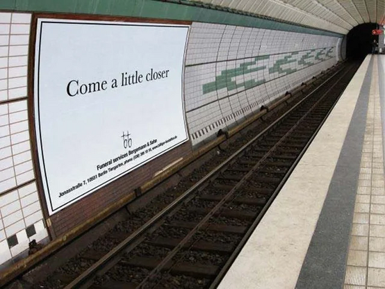 Funeral services advertisement in the metro that says "come a little closer", placed close to rails