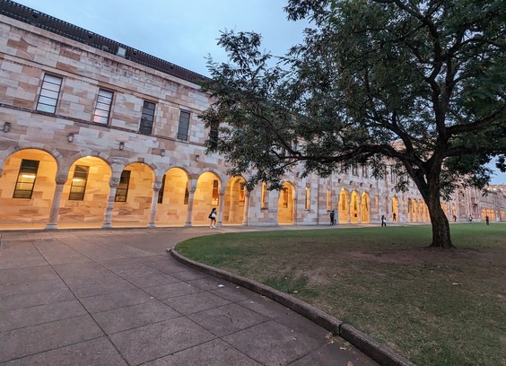 University of Queensland Great Court at dusk 
Sandstone arches march into the distance, warm light spilling out from the arches into the grassy court 