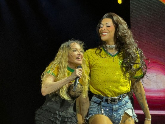 Cantoras Madonna e Pabllo Vittar, vestidas com uma camiseta semelhante à da seleção brasileira, durante o show final da turnê Celebration. Na imagem a proporção entre elas fica ressaltada com a Pabllo em tamanho muito maior que o da Madonna.