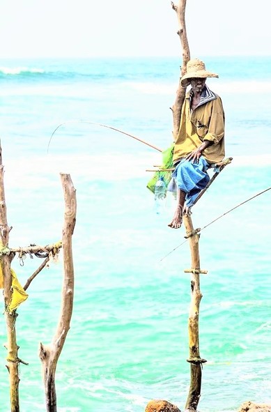 Fisher man sitting on pole in water fishing 