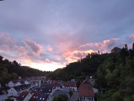 Blick in ein Tal mit Burg auf einem Berg bei Sonnenuntergang 