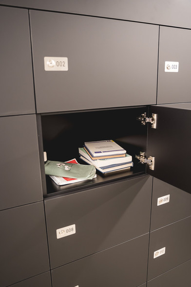 Bücher und Unterlagen liegen in einem geöffneten Bücherschließfach.