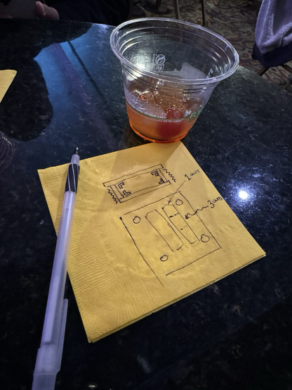 A cocktail napkin with a diagram on it and a cocktail off to the side. 