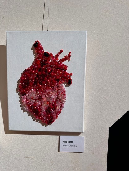 Obra expuesta: Un cuadro de un corazón realista hecho de bolas de colores en diferentes tonos de rojo