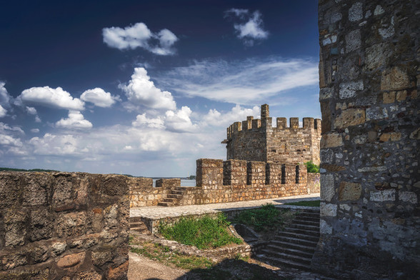 One hot summer day I visited Smederevo, a city in the heart of Serbia located right on the bank of the Danube. It is a beautiful city with many cultural sights and rich historical heritage.

One of the main sights of Smederevo is the old medieval fortress from the 15th century, Smederevo Fortress or Jerina town built by Serbian despot Djuradj Brankovic and his wife Jerina in just a few years, which was very fast at the time, so many builders died from exhaustion. People were looking for the culprit, and the wife of the Serbian despot Đurađ Branković - Jerina (Irena Kantakouzene) was blamed for that. It was called "Cursed Jerina" and that name has remained to this day. It was built in the period from 1428-1439. With its position at the confluence of the river Jezava and the Danube, it occupies an area of approximately 11 hectares, has the shape of an irregular triangle and consists of two parts - the Big City and the Small Town. It is the last major creation of a Serbian military building and one of the largest fortifications in Southeast Europe. Smederevo Fortress has been preserved in its integral form, including the castle - Small Town and the town surrounded by ramparts and towers.
It is definitely the main attraction of Smederevo and you must see it if you ever come to this city.

One July day in Smederevo, Serbia. From the collection Castles, fortresses and towers.
