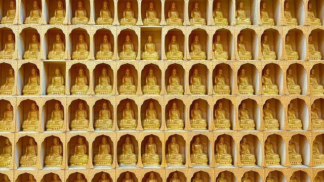 Wall with many small Buddha statues in nooks.