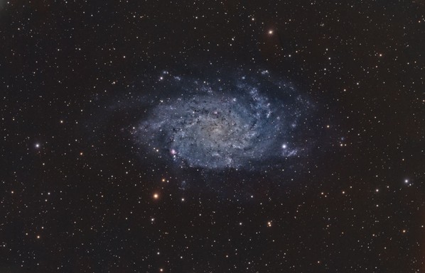 Messier 33 Triangulum Galaxy:
Black background with many stars of varying brightness spread throughout.

At center is a spiral galaxy with a very faint yellow core and blue spiral arms. Gives an overall oval shape.
