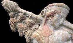 A relief of Dionysos carrying his thyrsos staff over his shoulder from which several clusters of grapes hang. There are traces of reddish colour left in the god's hair and head scarf.