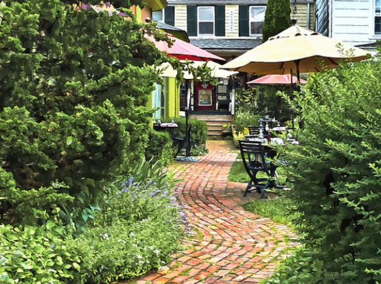 Restaurant in Cold Spring, NY in Putnam County.  A quaint brick pathway leads through a lush garden area to a cozy outdoor café with tables and umbrellas.