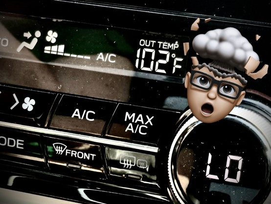 A photo of a car’s climate controls including an outside temperature indicator reporting 102 degrees Fahrenheit. A “mind blown” Memoji sticker is placed next to the 102 temperature.