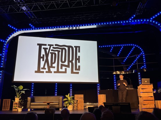 Chris Campo on stage. Screen showing an “Explore” lettering made by her. 