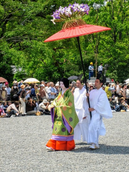 Large parasols, decorated with flowers, protect women attendants from the hot sun.