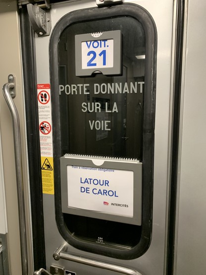 Inside door of train. Destination sign shows Latour de Carol