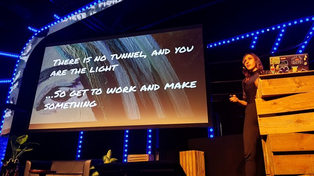 Natalya Shelburne on stage of the beyond tellerrand Düsseldorf 2024, standing next to her slide saying "there is no tunnel, and your are the light. ...so get to work and make something."