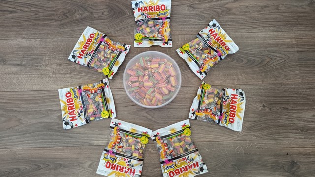 7 Tüten Haribo Pixel Fan Edition verteilt um eine Dose Haribo Rainbow Pixel