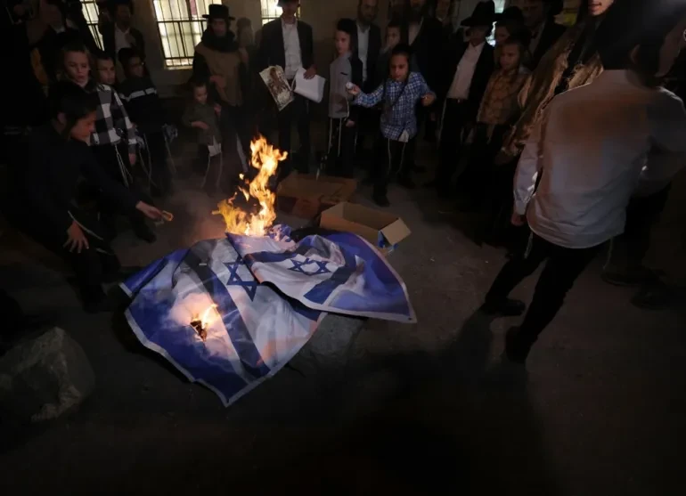 Ultra-orthodox Jews burn Israeli national flags during an anti-Independence Day protest at their Meah Shearim neighbourhood in Jerusalem, on May 14, 2024 [Atef Safadi/EPA]