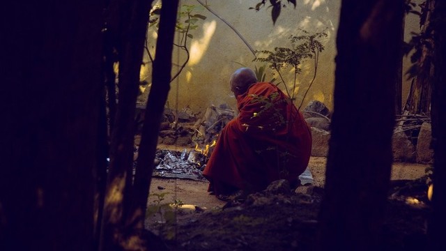 Monk tending a fire.