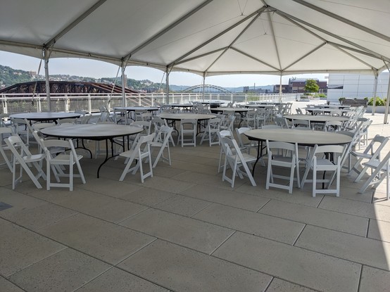 Tables outside on the fourth floor roof with a brown bridge in the background