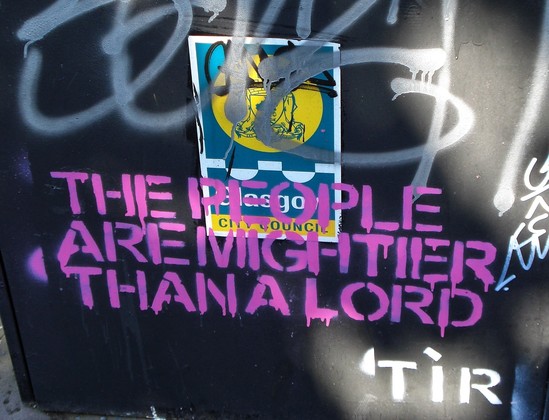 Stenciled words on a graffiti ridden Glasgow public metal bin. Pink paint.
Text: The people are mightier than a lord