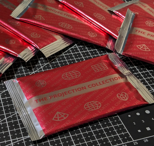 Several sealed card packs in red with white accents that have the words THE PROJECTION COLLECTION written on them.
