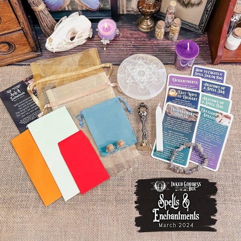 An assortment of spell-writing and spell-casting materials sit on a burlap-covered surface. From left to right, there are three colors and sizes of papers and envelopes; three organza bags; two small empty cork-stoppered vials; a selenite charging plate engraved with Metatron's Cube sacred geometry; a metal seal and a stick of white sealing wax; seven Eclectic Witch Deck cards; and a labradorite chip bracelet. These are the contents of the exclusive March 2024 "Spells & Enchantments" IGC Box.