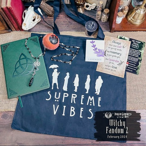 An assortment of items inspired by our favorite pop culture witches are arranged on a burlap-covered surface. The items include a Charmed Inspired Book of Shadows, an AHS Coven Inspired Tote, Nancy's Rosary Beads, Rowena's Kiss Bath Bomb, Dark Baptism Votive Candle, and Practical Magic Inspired Art Card with Lavender Seeds DIY. These are the contents of the exclusive February 2024 "Witchy Fandom 2" Inked Goddess Creations Box.