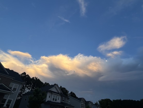 This cloud looks like it's got a ball of orange-pinkish glow nestled inside it. The entire cloud is wispy, and glowing this bright orange-pinkish color where the sunlight is hitting it.