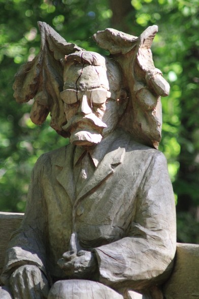 Figur geschnitzt aus Holz, die einen Mann mit Bart und Brille zeigt.